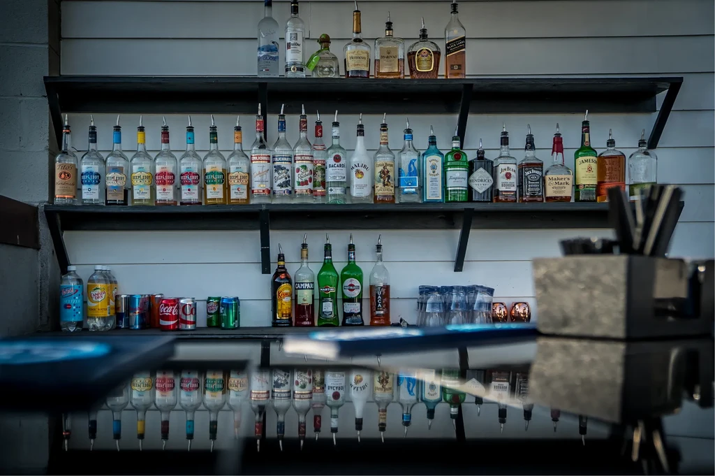 Well-stocked bar with liquor bottles, pour spouts, and various mixers.