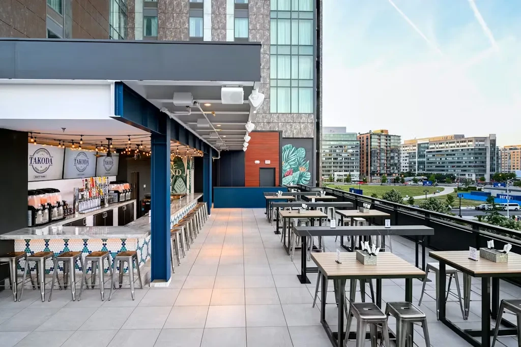 Empty modern rooftop bar and patio overlooking a cityscape.