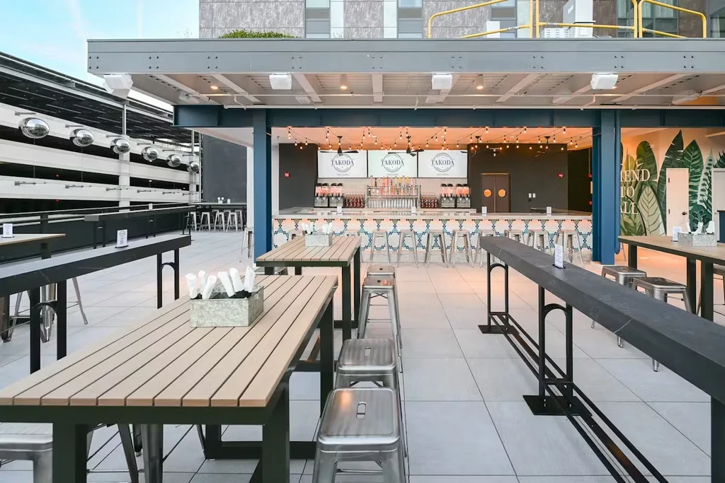 Empty modern rooftop bar with TAKODA logo and tropical mural.