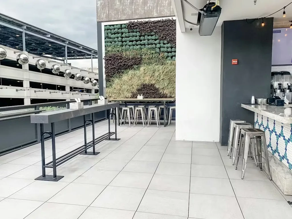 Outdoor patio featuring a mosaic bar, living wall, and high-top tables.