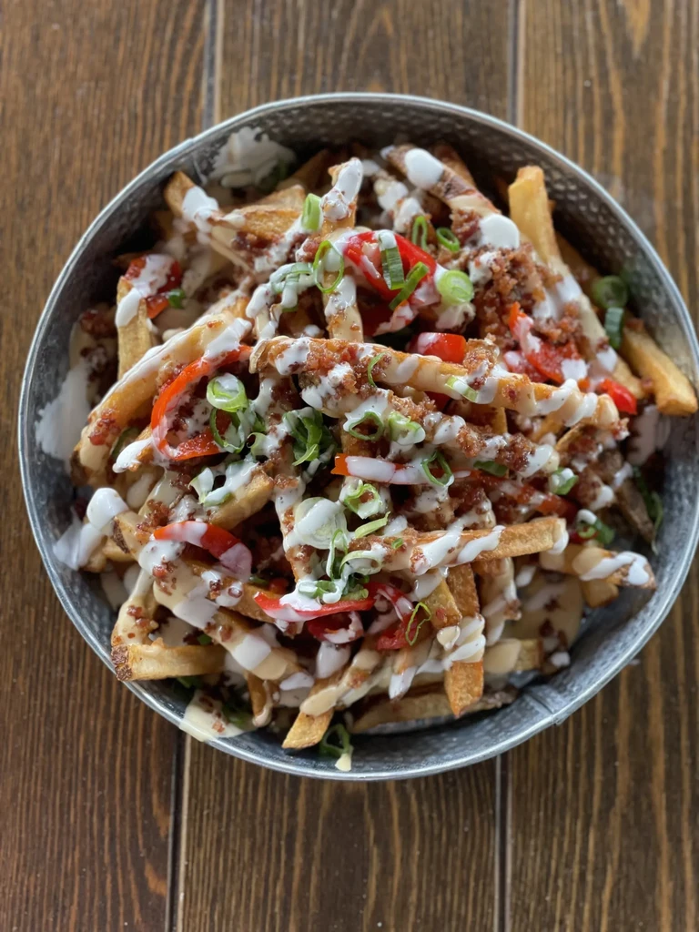 Loaded french fries with creamy sauce, bacon, bell pepper, green onions.
