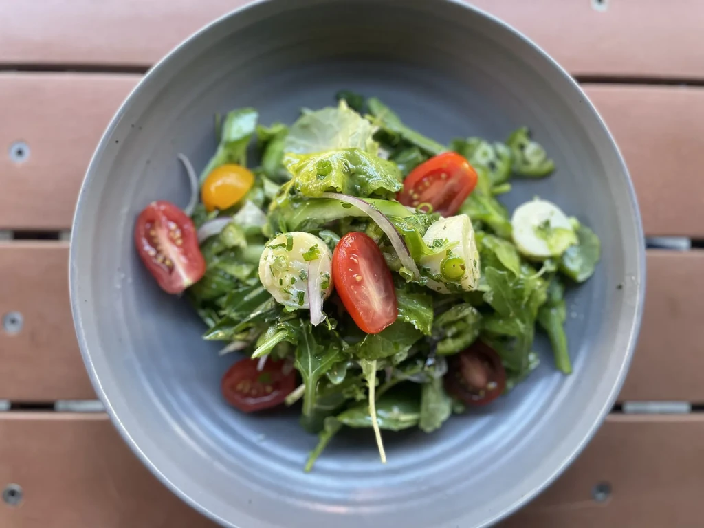 Top-down view of a colorful salad with greens, tomatoes, and mozzarella.