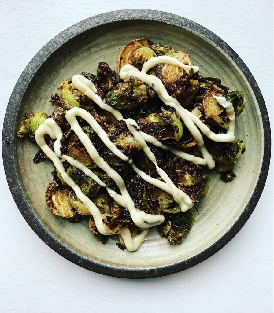 Caramelized roasted brussels sprouts with creamy sauce in a rustic bowl.