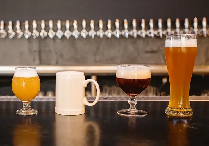 Three beer glasses and an inverted mug on a bar.