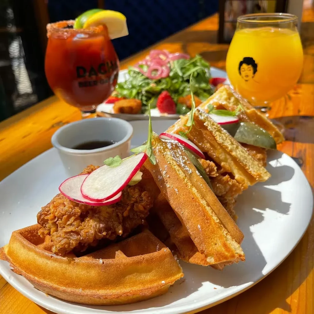 Close-up of chicken and waffles, Bloody Mary, and salad on a table.