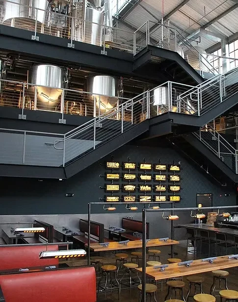 Empty modern brewpub with large brewing tanks above dining area.