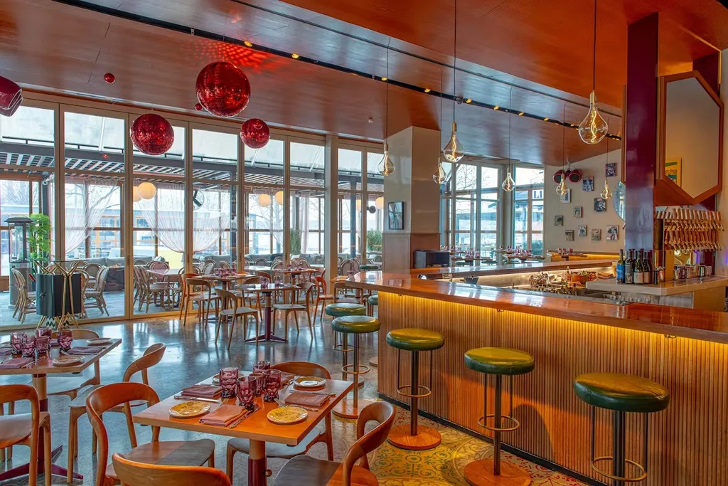 Empty modern restaurant interior with warm wood, bar, and disco balls.