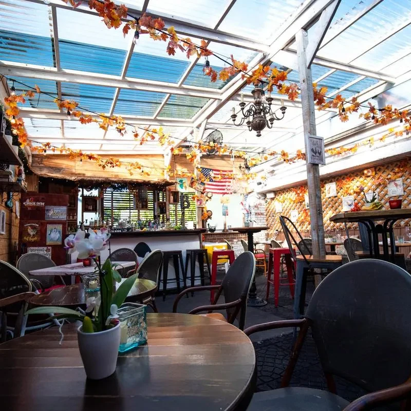Bright, empty restaurant bar with rustic decor, string lights, autumn garlands.