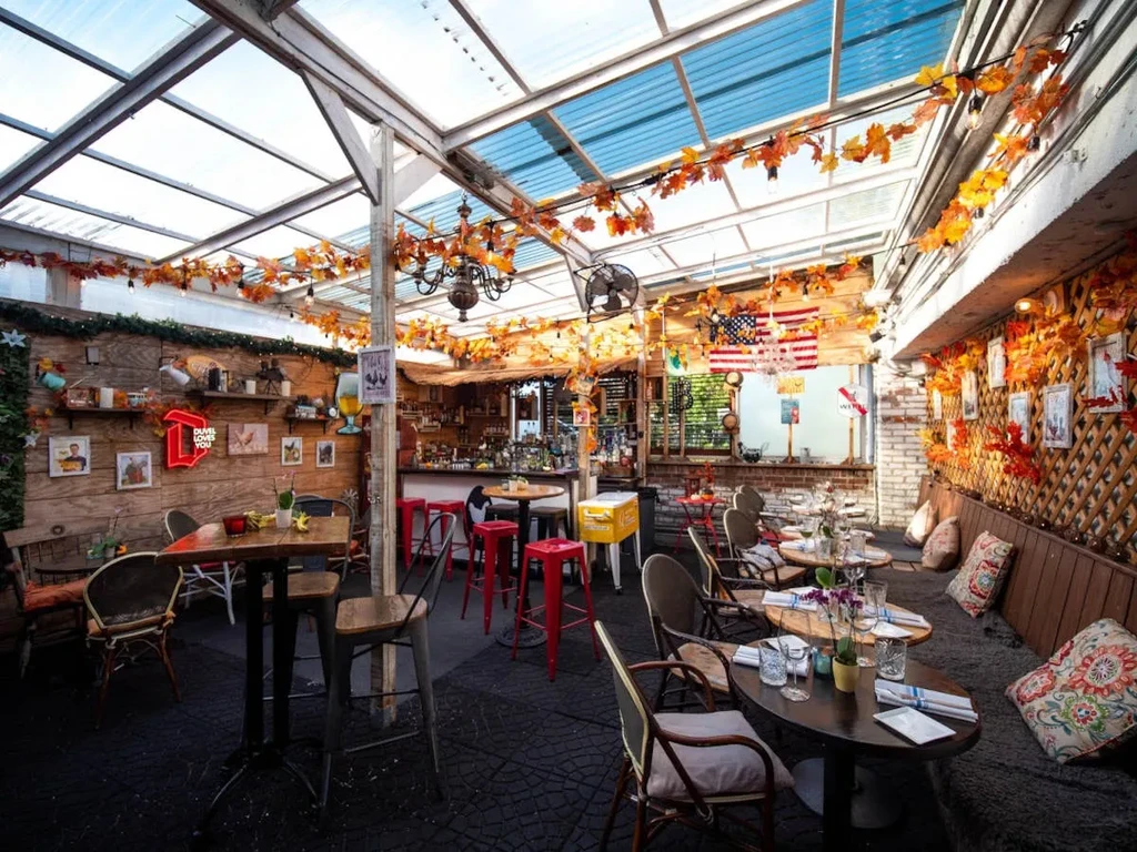 Enclosed patio restaurant decorated with autumn leaves, neon sign, and American flag.