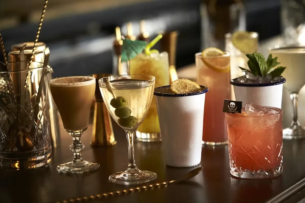 Diverse cocktails and golden bar tools displayed on a dark counter.