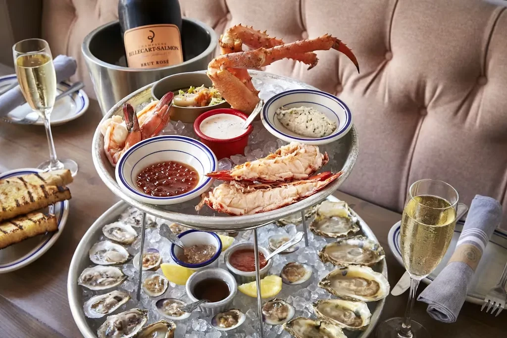 Lavish two-tiered seafood tower with crab, lobster, shrimp, oysters, and champagne.