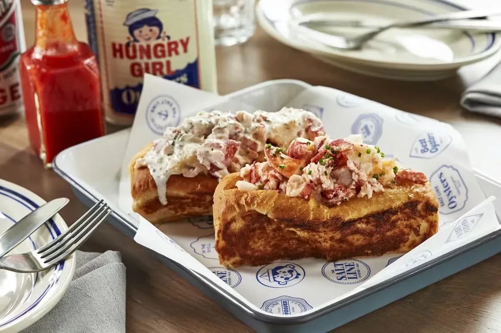 Two generously filled lobster rolls with chives and creamy sauce.