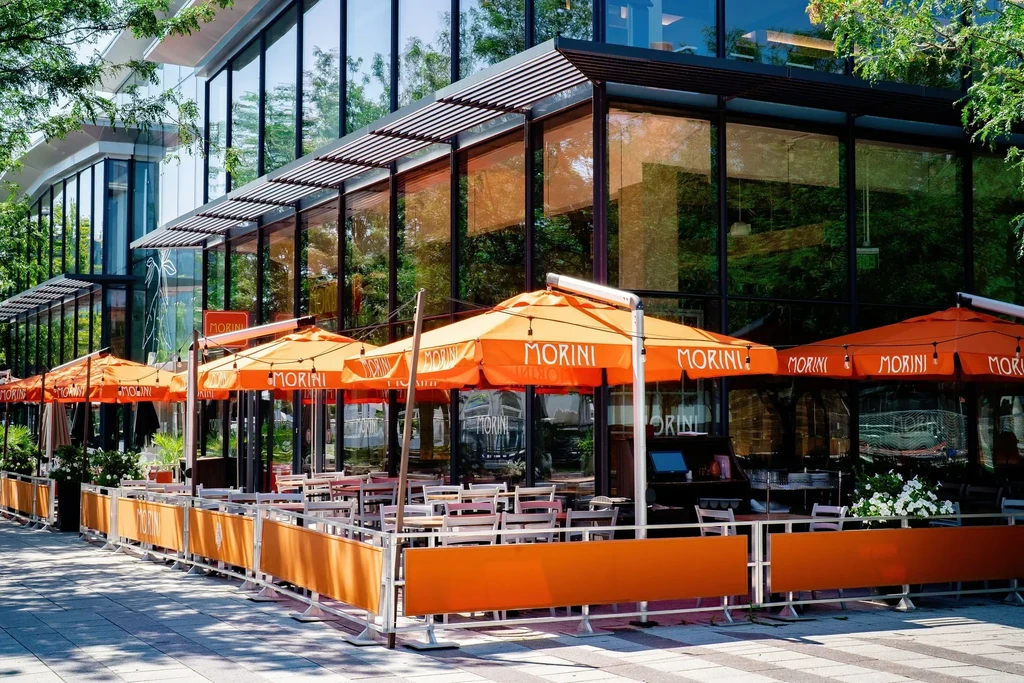 Modern MORINI restaurant outdoor dining with vibrant orange umbrellas.