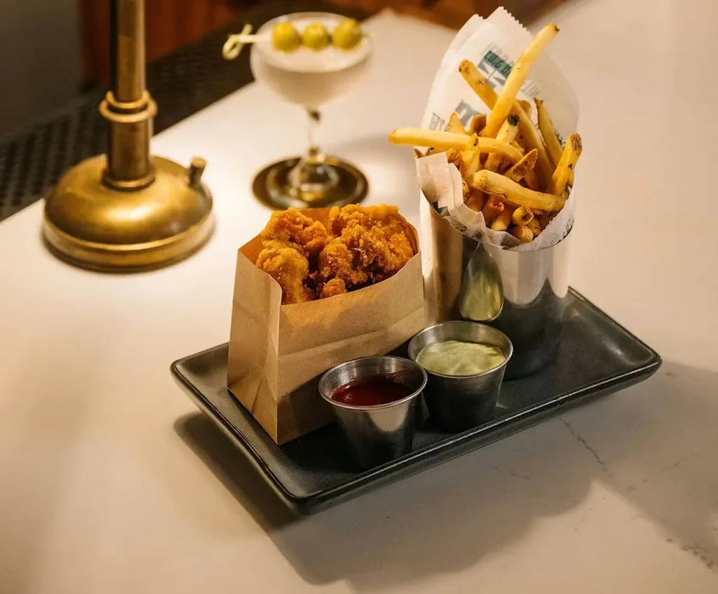 Close-up of fried chicken, fries, sauces, and a martini.