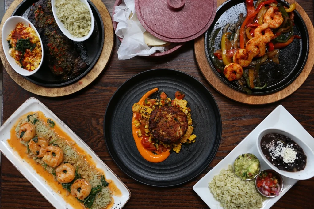 Overhead view of diverse Mexican-style food dishes on a wooden table.