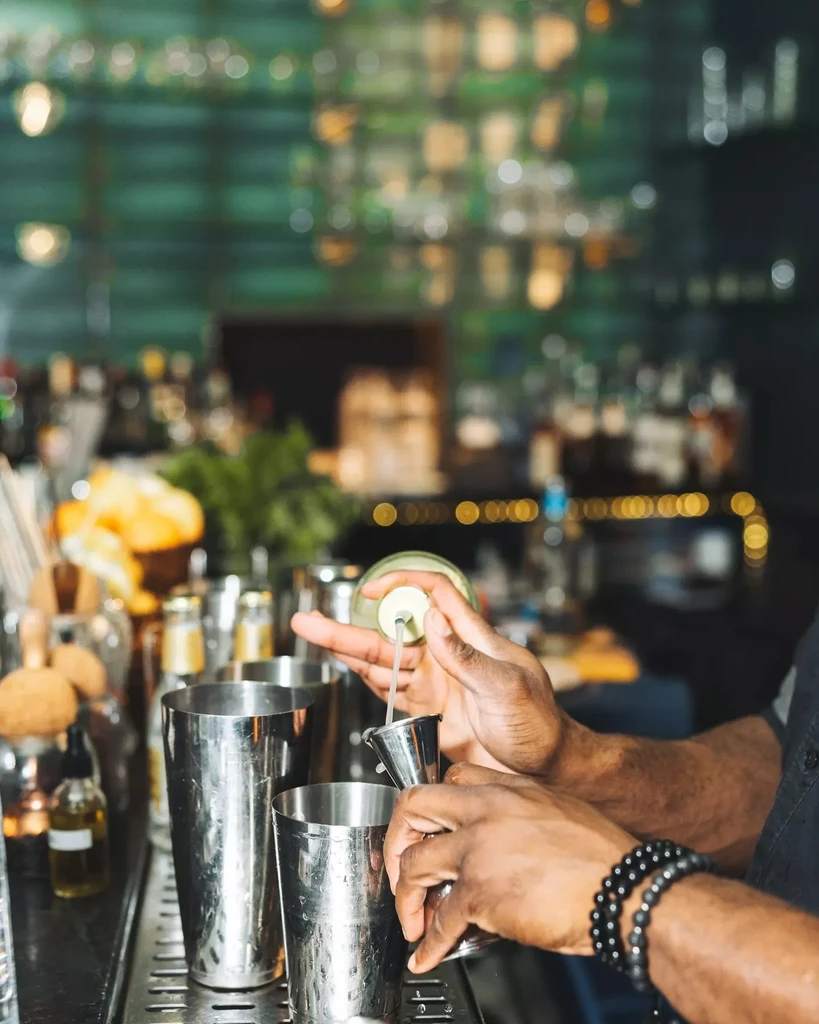 Close-up: Bartender's hands pouring spirits into a jigger at a bar.