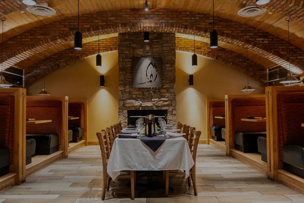 Sophisticated restaurant with long dining table, stone fireplace, and booth seating.