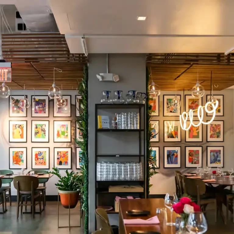 Modern restaurant interior with colorful abstract art and empty dining tables.