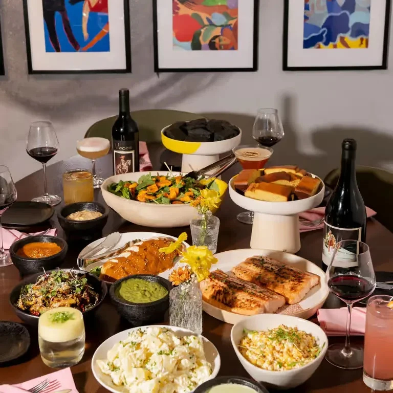 Elegant dining table laden with gourmet fish, sides, wine, and cocktails.