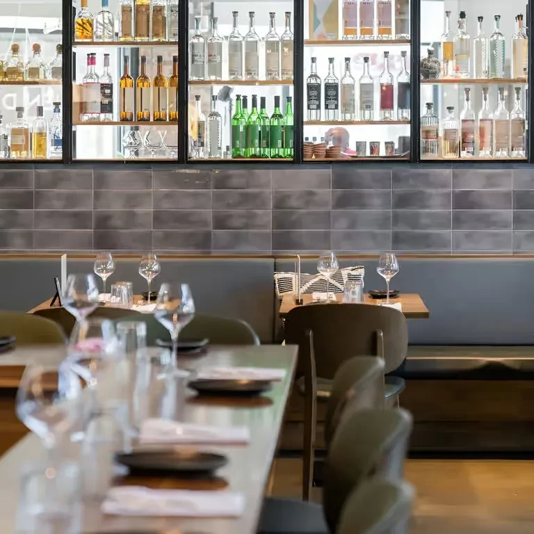 Elegantly set modern restaurant with tables and illuminated spirits display.