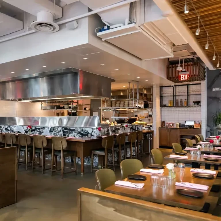 Empty modern restaurant interior with wooden tables and open kitchen.