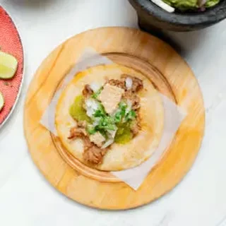 Taco with meat, onion, cilantro, salsa, chicharron on wooden plate.