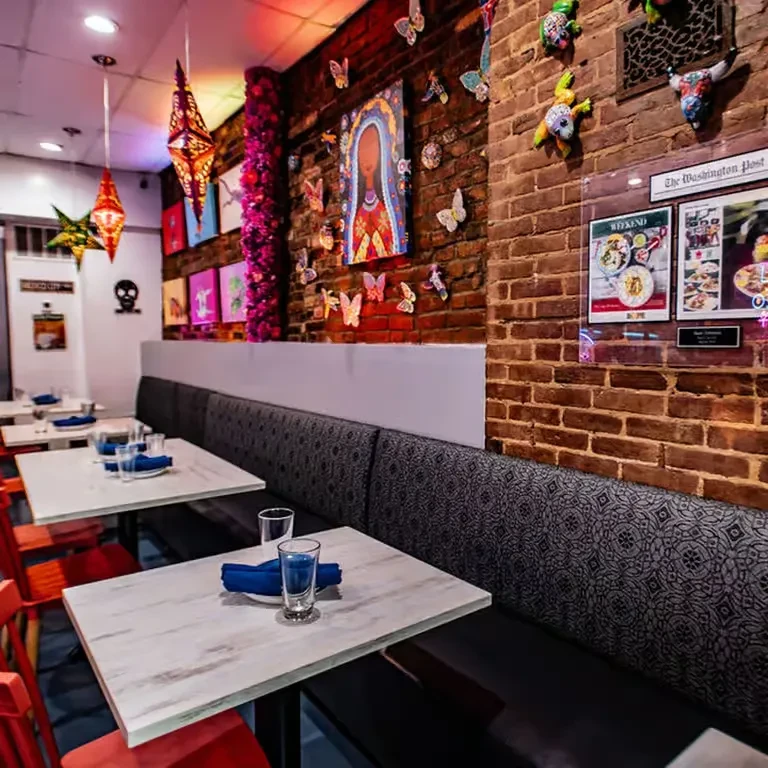 Colorful restaurant interior with brick wall decor, booths, and red chairs.