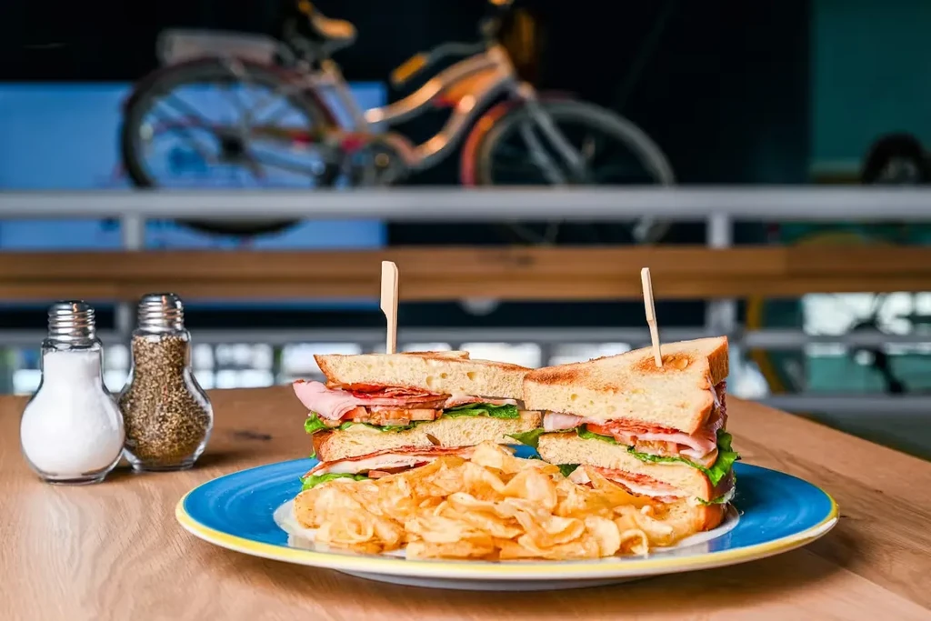 Club sandwich, ridged chips, salt, and pepper on a blue plate.
