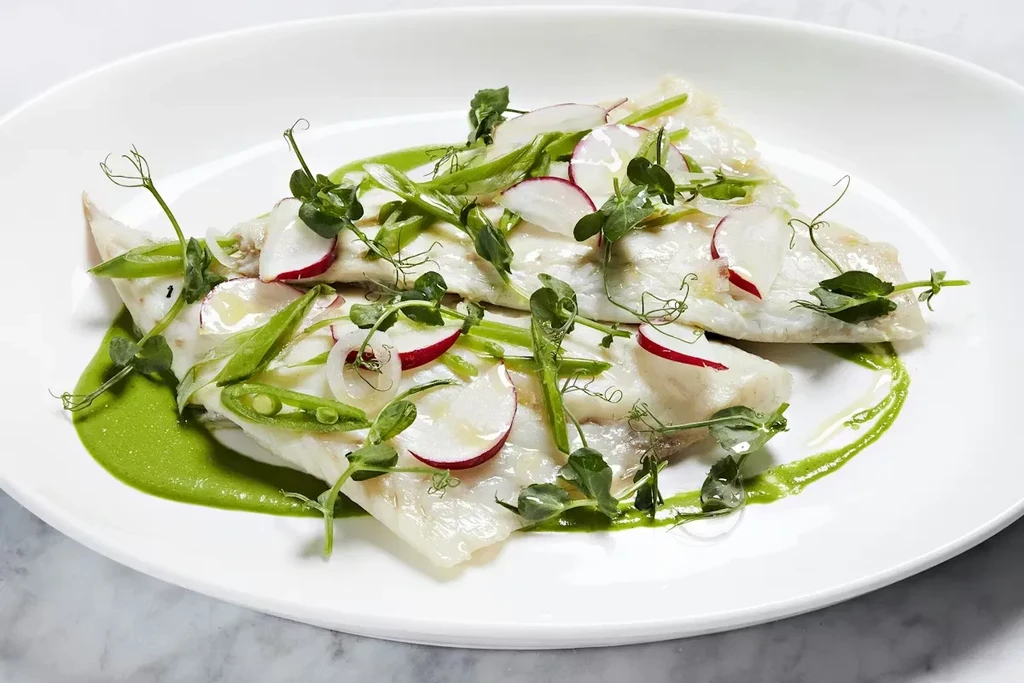 Delicate white fish on green puree, garnished with radishes and peas.