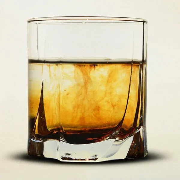 Faceted glass with amber drink and swirling dark patterns.
