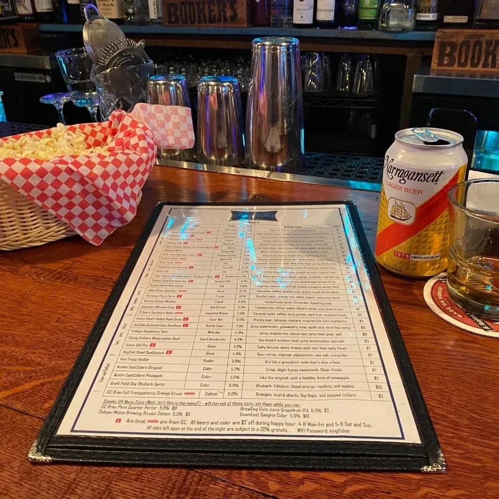 Menu, popcorn, and Narragansett beer on a dim bar counter.