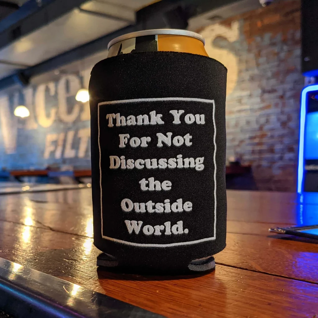 Can in black koozie reads 'Thank You For Not Discussing the Outside World'.