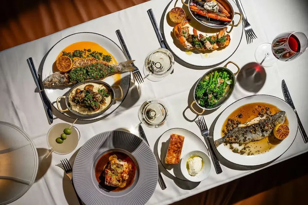 Overhead view of an elegant dining table with gourmet food and drinks.