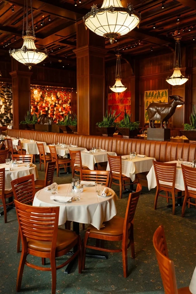 Spacious, elegant, empty restaurant with dark wood and a goat sculpture.