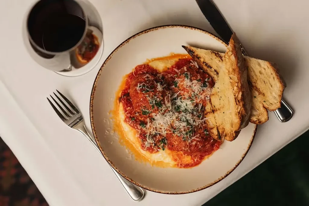 Meatballs in red sauce, cheese, herbs, creamy base, grilled bread, and wine.