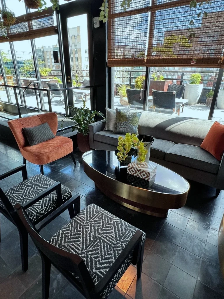 Bright modern lounge with varied seating, green plants, and urban view.