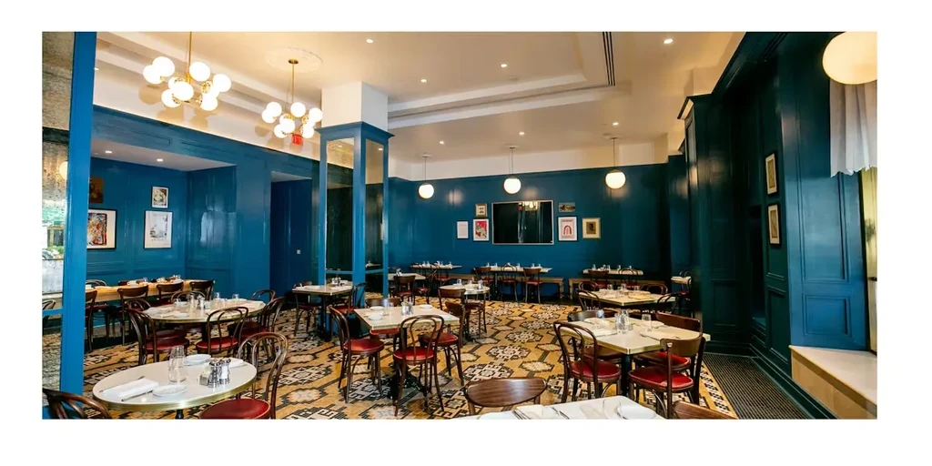 Upscale restaurant interior with teal walls, geometric floor, and marble tables.