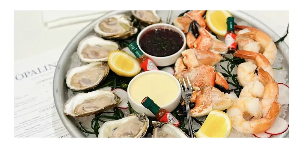 Seafood platter with oysters, shrimp, crab, sauces, and lemon on ice.