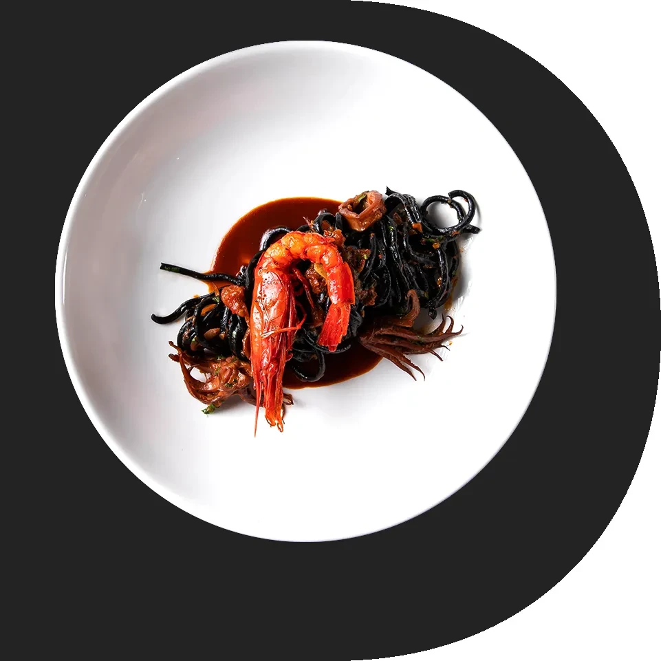 Black pasta with red prawn and calamari in dark sauce.