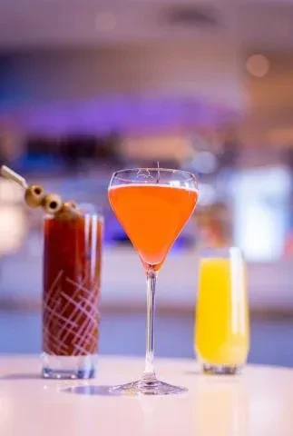 Three vibrant drinks: a Bloody Mary, orange cocktail, and yellow beverage.