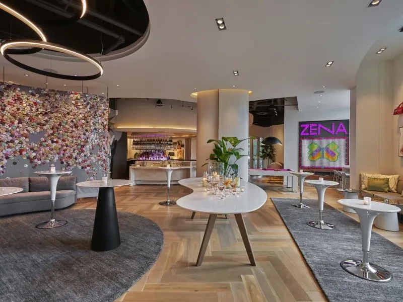 Upscale contemporary bar with varied seating, floral art, ZENA sign.
