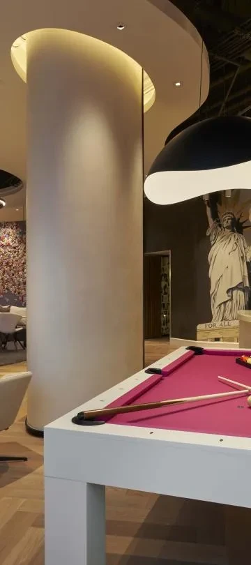 Modern lounge with a magenta pool table and Statue of Liberty mural.