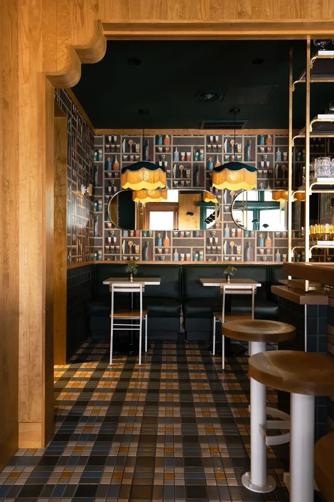 Restaurant interior with bar, checkered floor, and bottle-themed wallpaper.