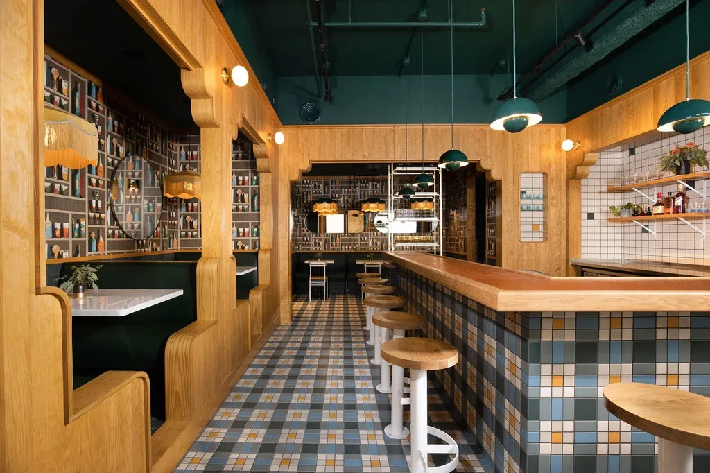 Stylish restaurant interior combines light wood, dark green, and patterned tiles.