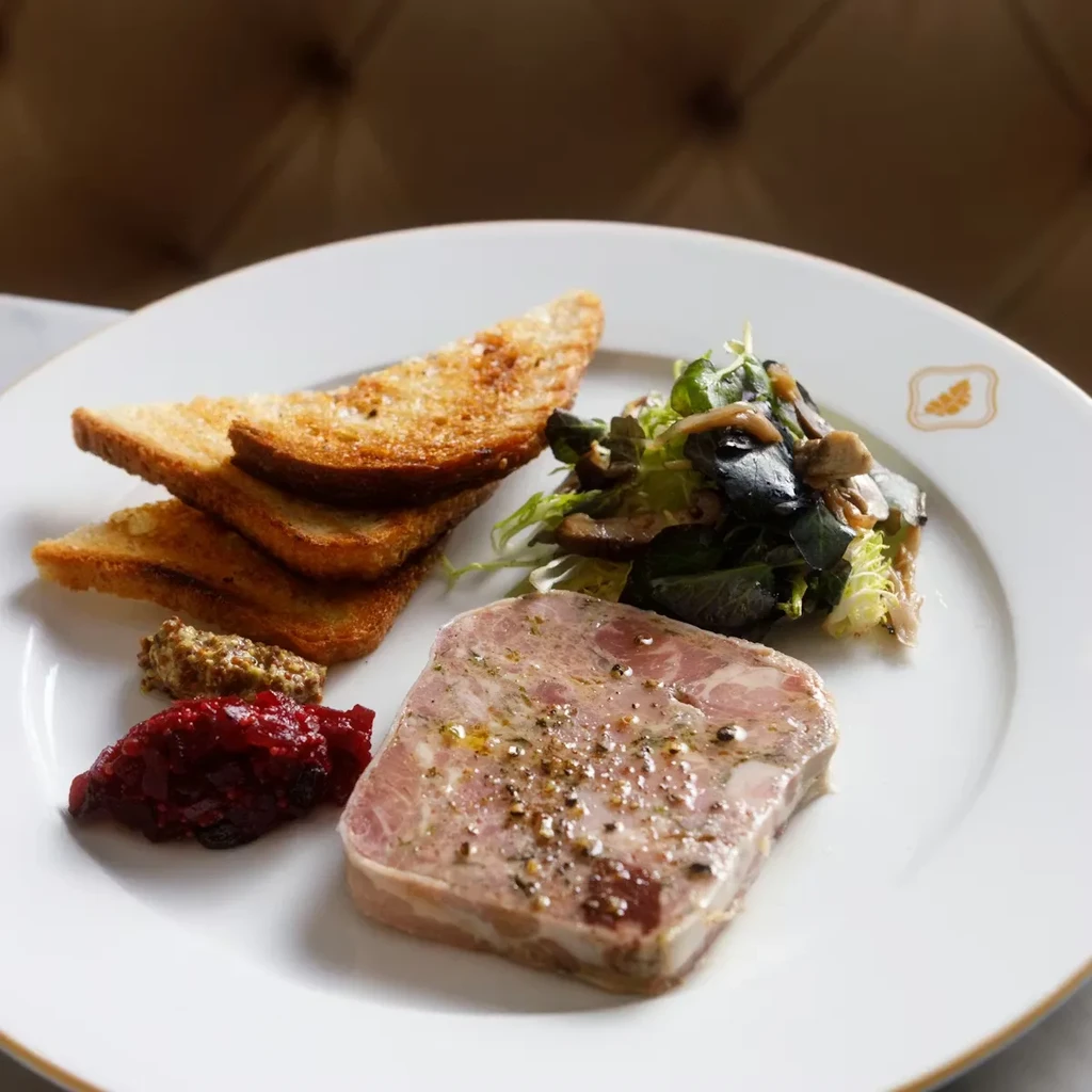 Pâté, compote, mustard, toast, and salad on a white plate.