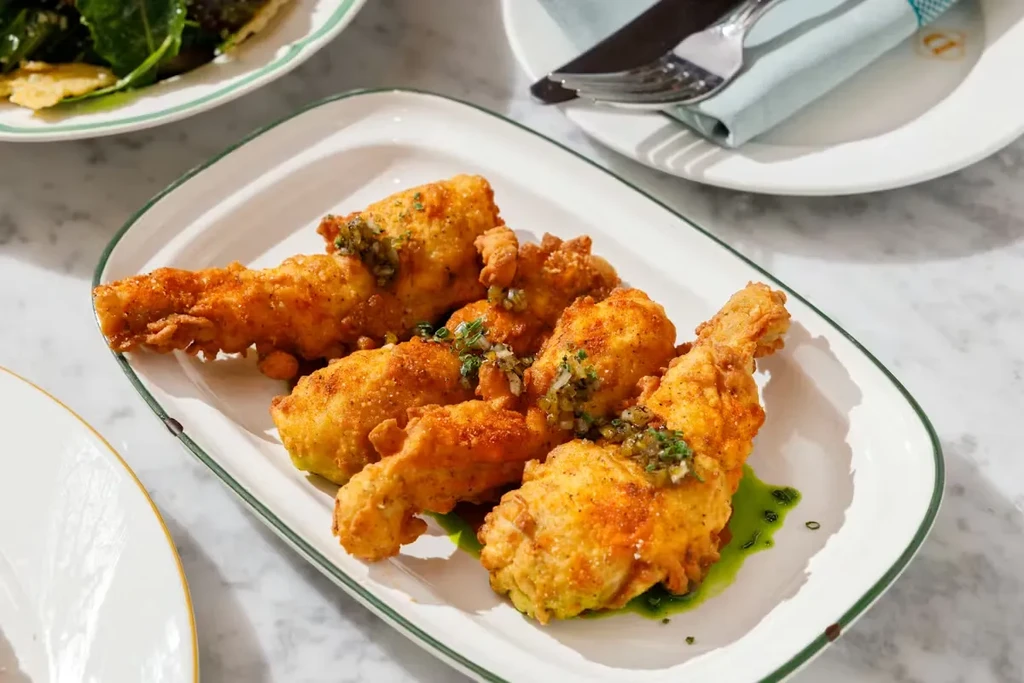 Golden-brown fried food with green sauce on a restaurant plate.