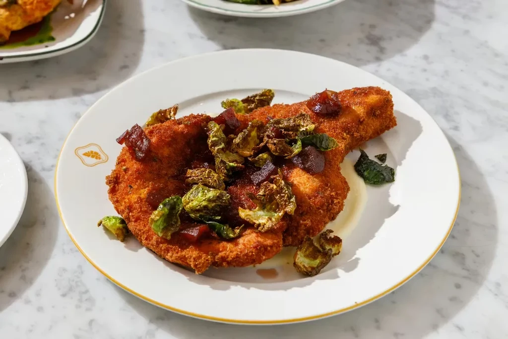 Crispy breaded cutlet topped with roasted Brussels sprouts and red relish.