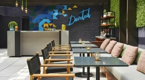 Modern restaurant interior with bar, banquette seating, and a 'Dovetail' sign.