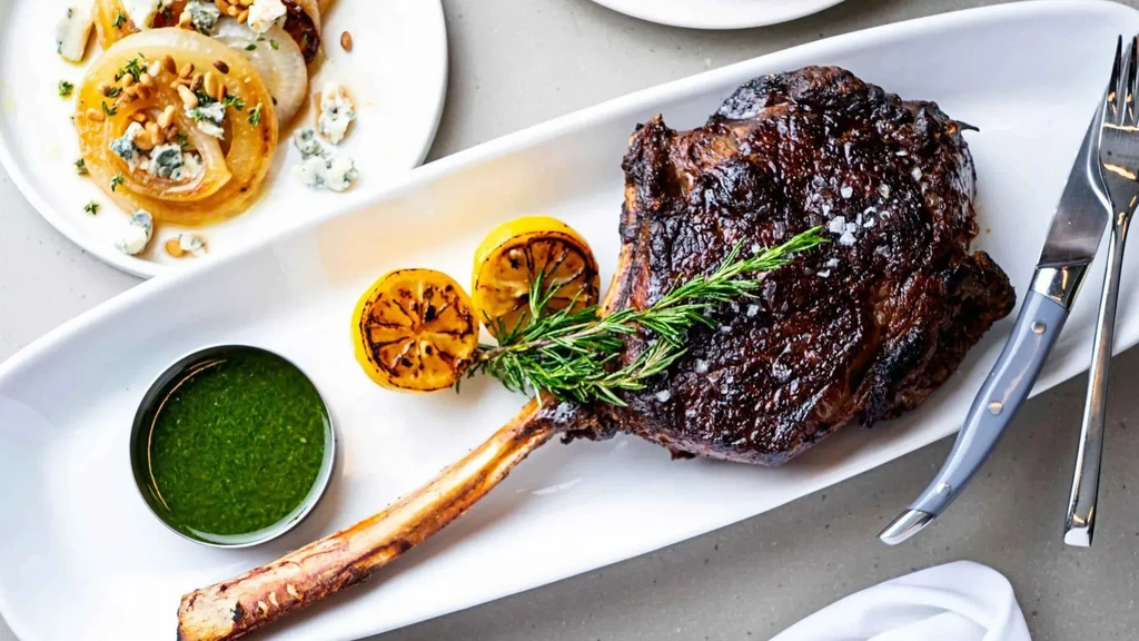 Seared bone-in steak, green sauce, charred lemons, roasted onions.