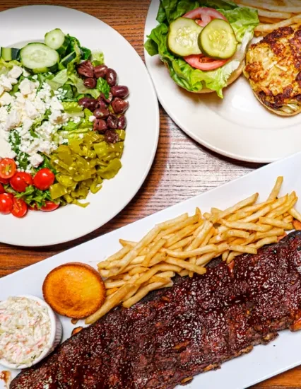 Overhead view: BBQ ribs, salad, and a sandwich on wooden table.